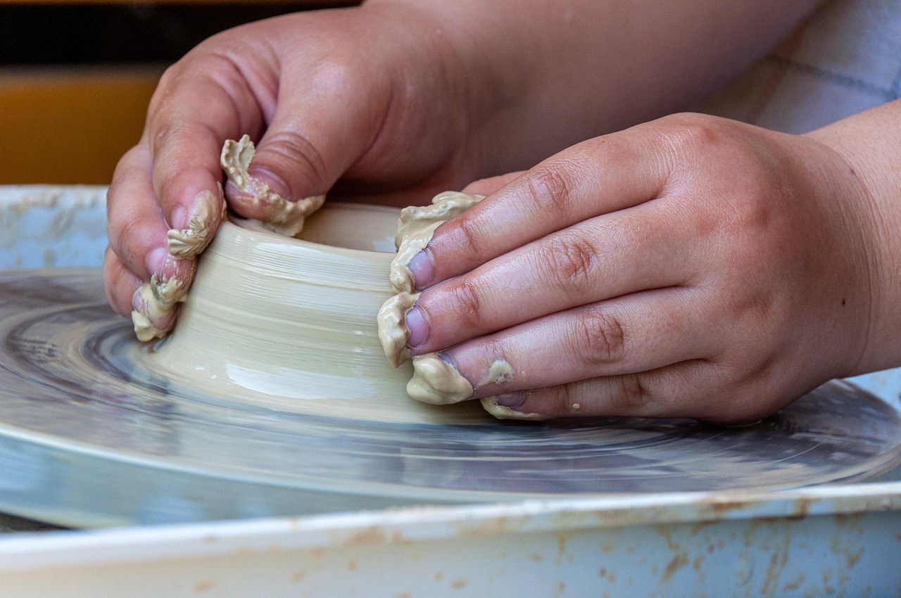 Hands shaping clay on a pottery wheel